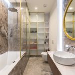 Modern light bathroom interior with white sink and faucet on counter near mirror and toilet near bath