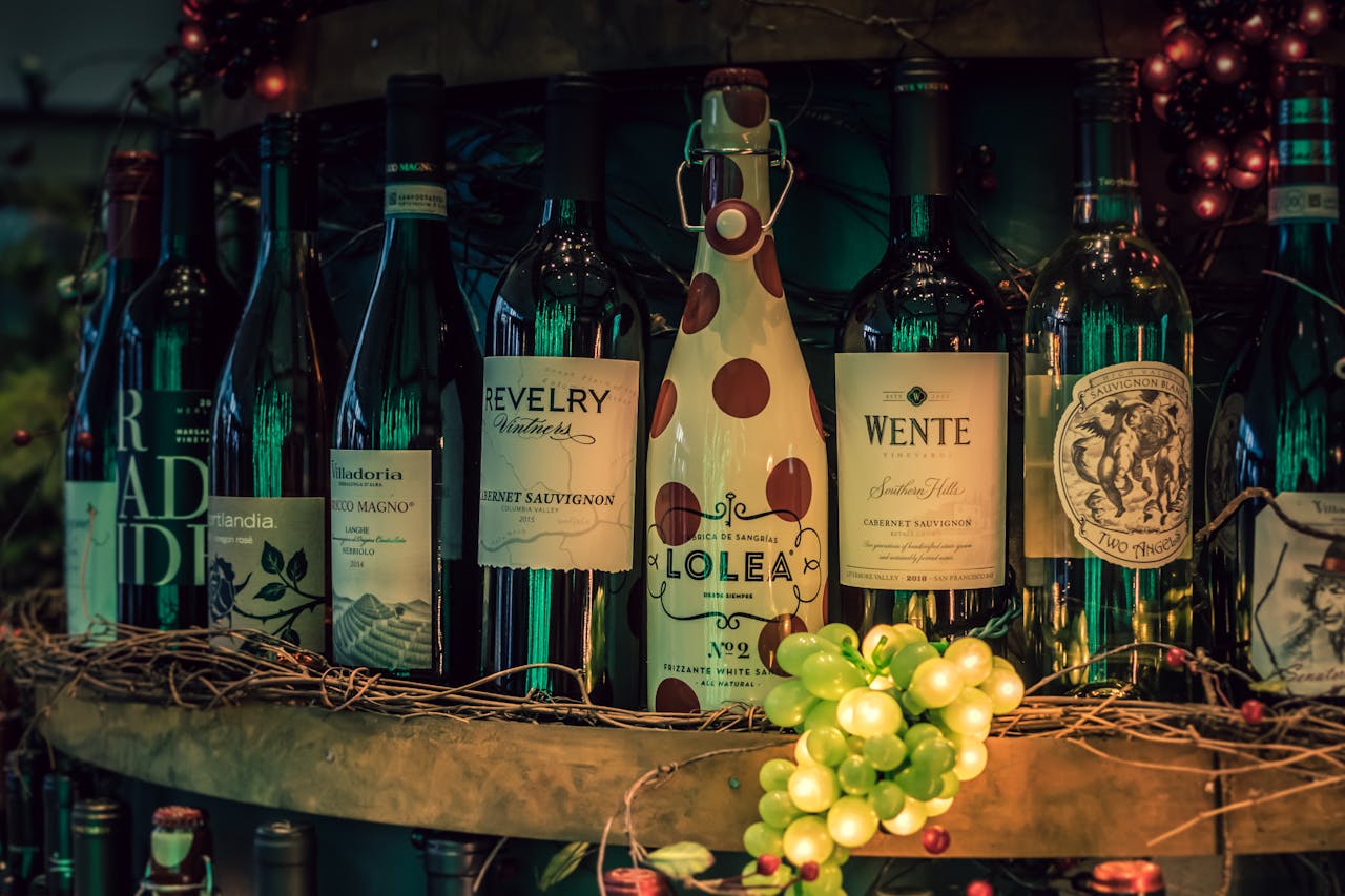 A showcase of assorted wine bottles displayed on a rustic shelf with decorative grapevine.