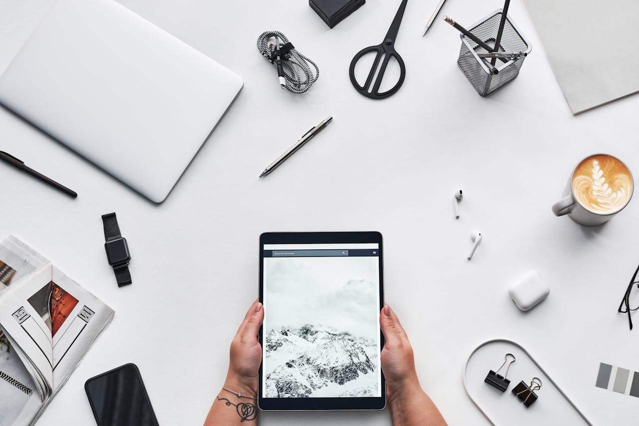 hero-img Flat lay of a modern workspace featuring a tablet, gadgets, and coffee for creative work.