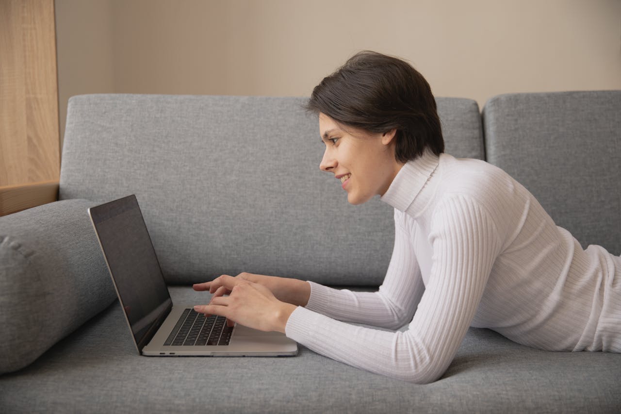 Crafting Captivating Headlines: Your awesome post title goes here Woman working remotely on a laptop at home, lying on a comfortable sofa.